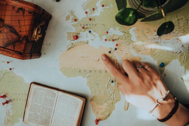 Close-up of a hand pointing on a map, surrounded by travel essentials.